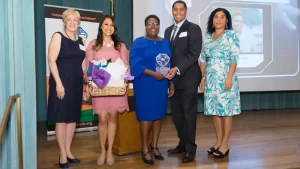 Five people pose with an award and gift basket at a STEM event.