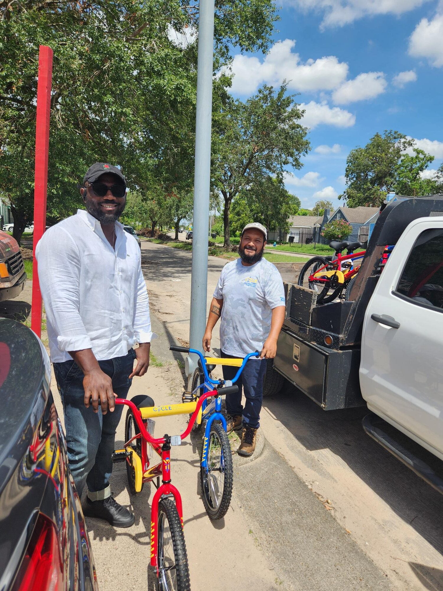 Two men with bikes, one red and yellow, one blue. C stem visible on the yellow handlebars.