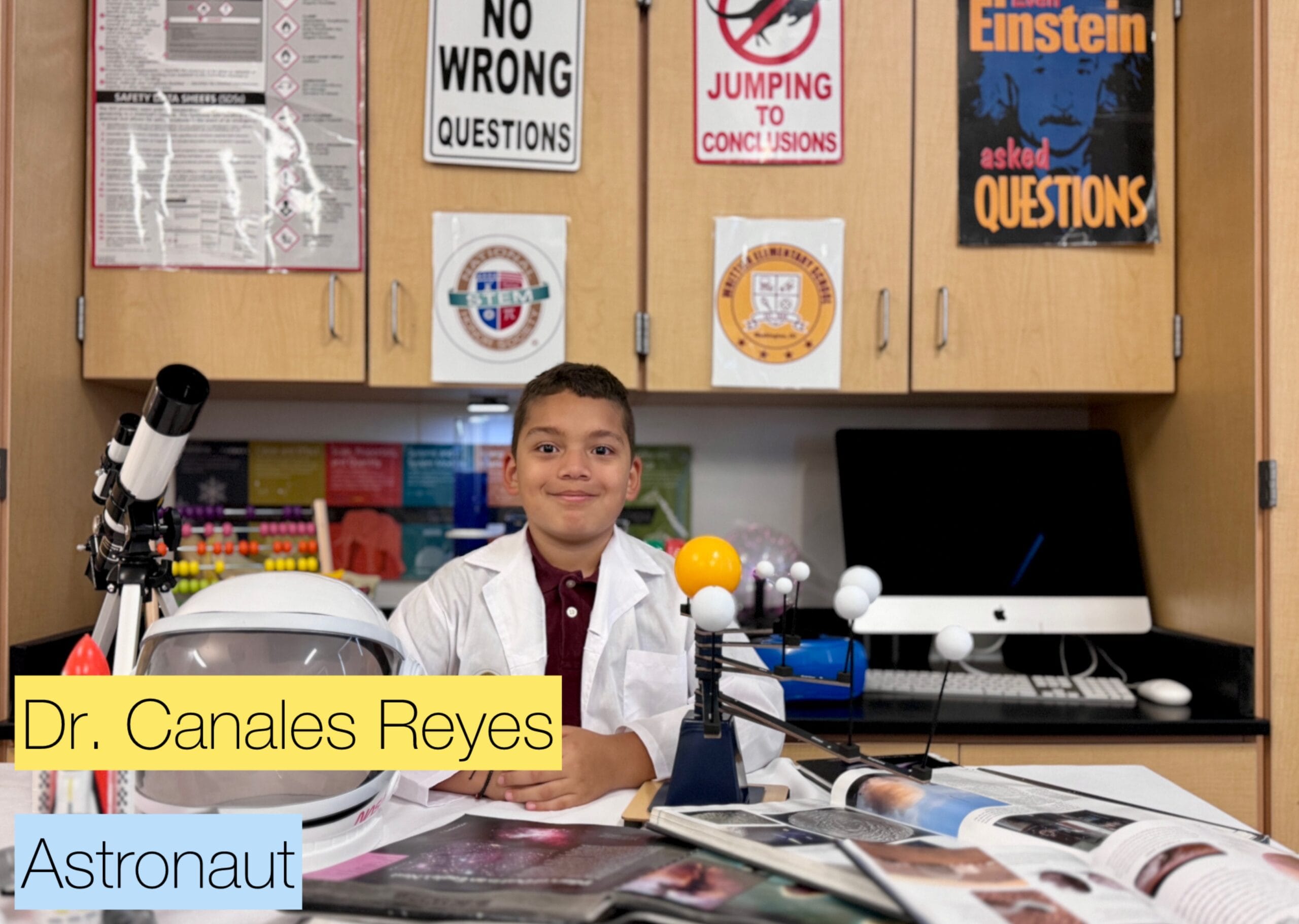 Young student in lab coat, surrounded by science & space items. "No Wrong Questions". STEM education in action.